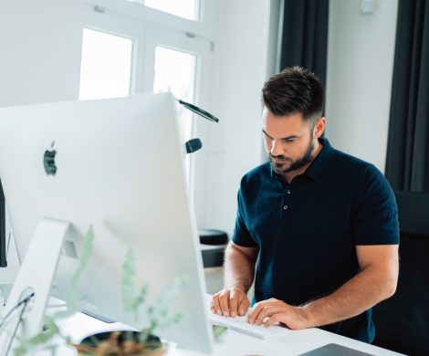 man in blue polo shirt using laptop computer