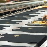 a person cutting fabric on a conveyor belt
